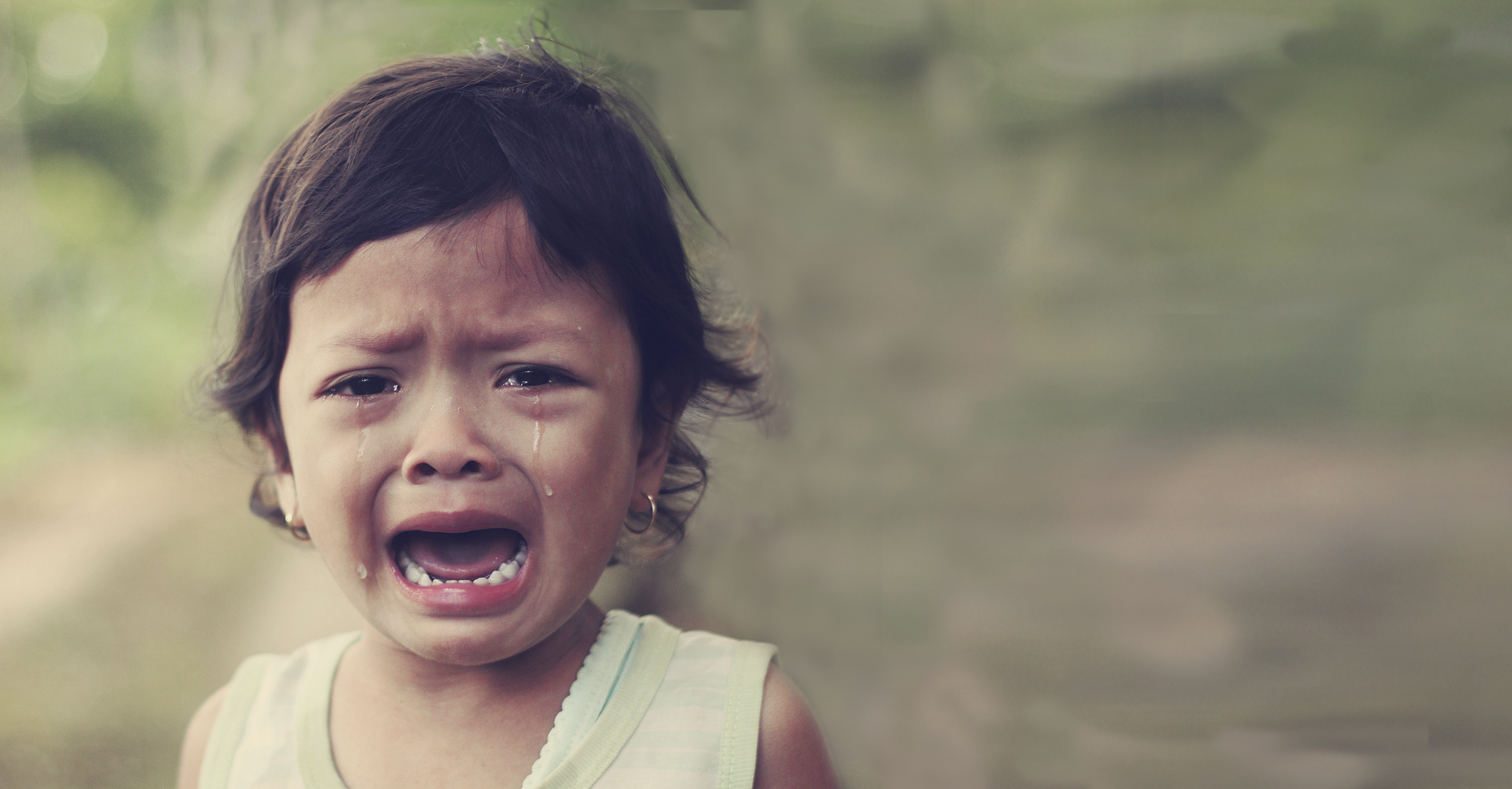Young child crying in nature with tears streaming down her face