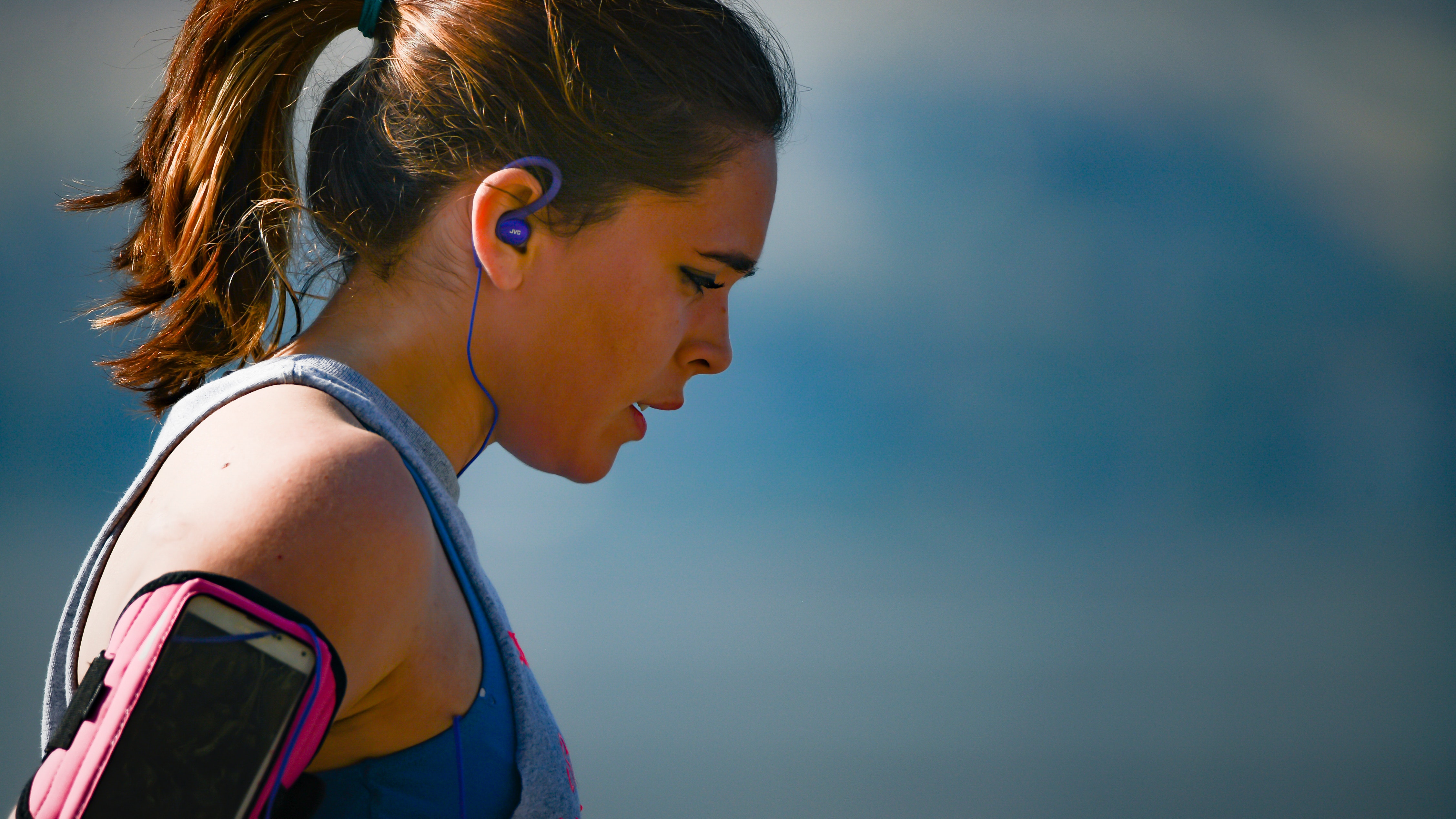 A side profile view of a woman's head. She is wearing headphones and activewear is about to commence exercise.