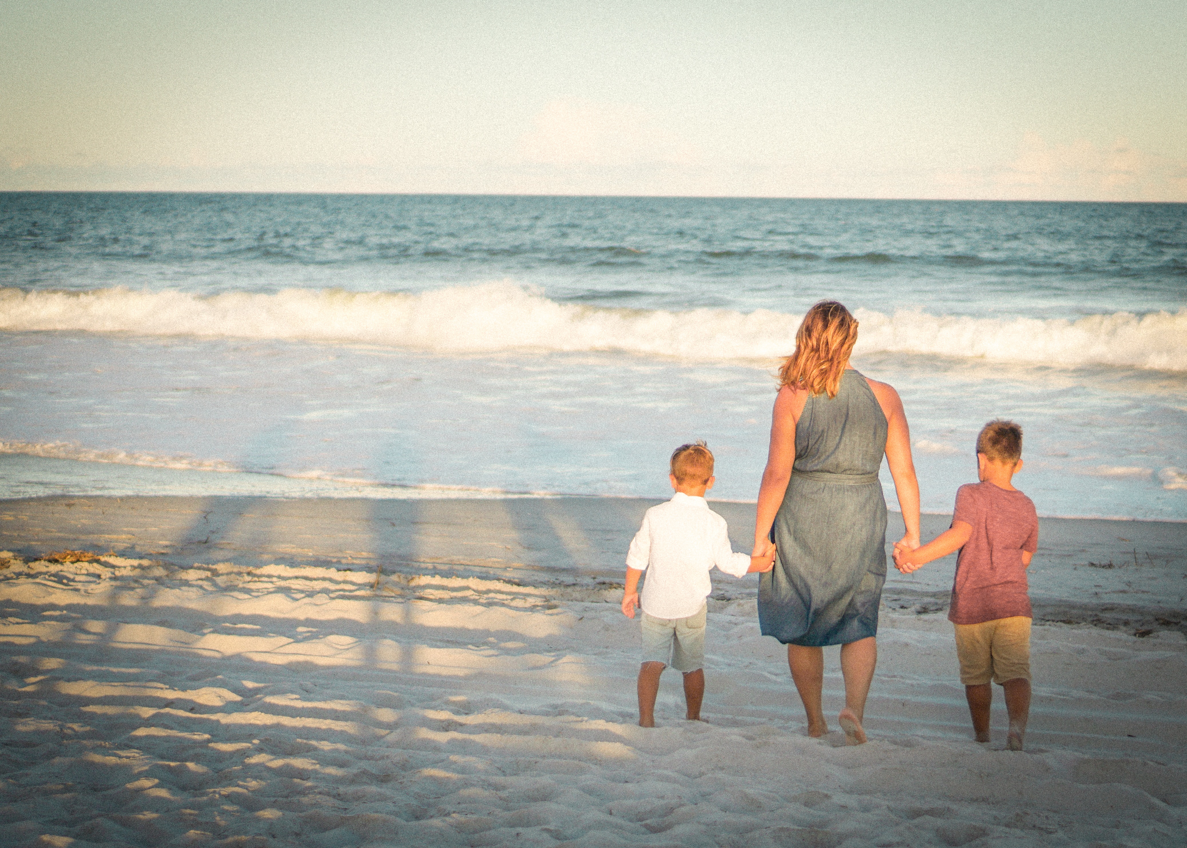 mother walking on beach with 2 kids