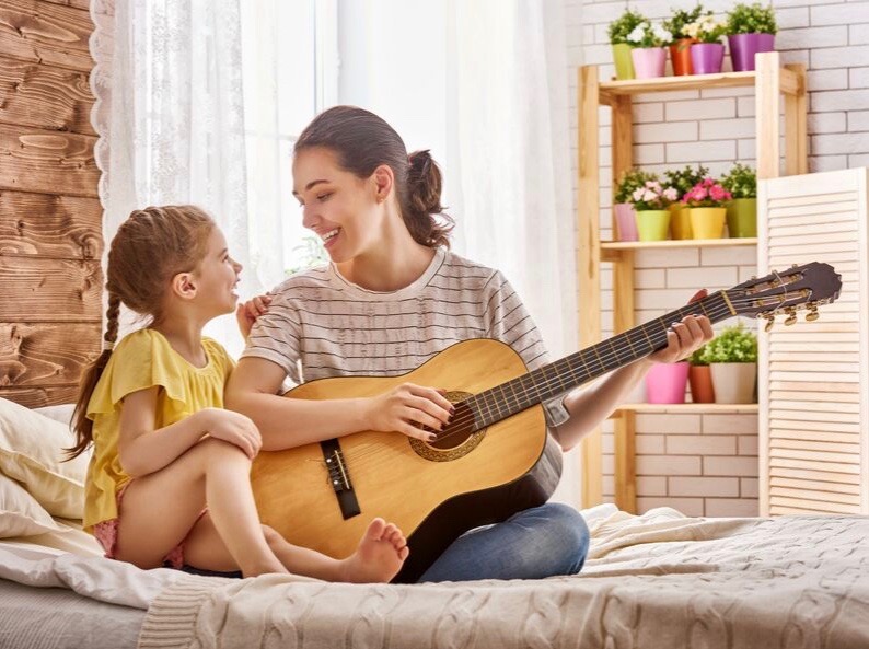 woman and child playing the guitar and singing