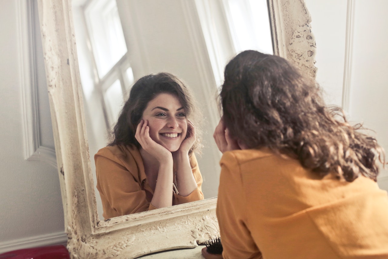 Young woman looking in the mirror smiling