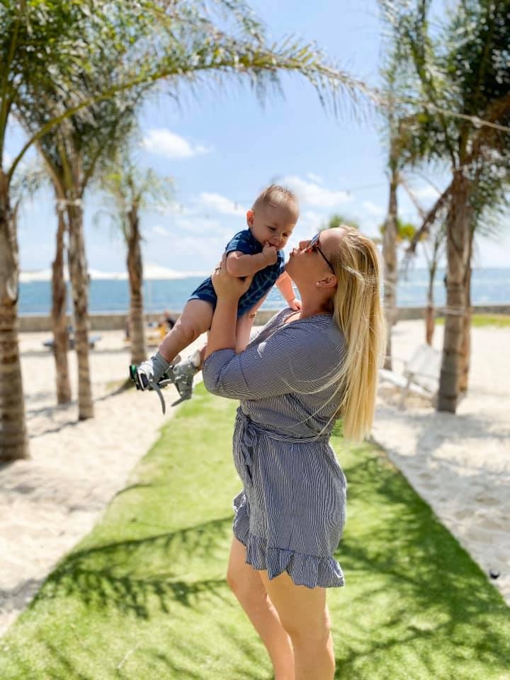 Mom on a beach kissing her sweet child