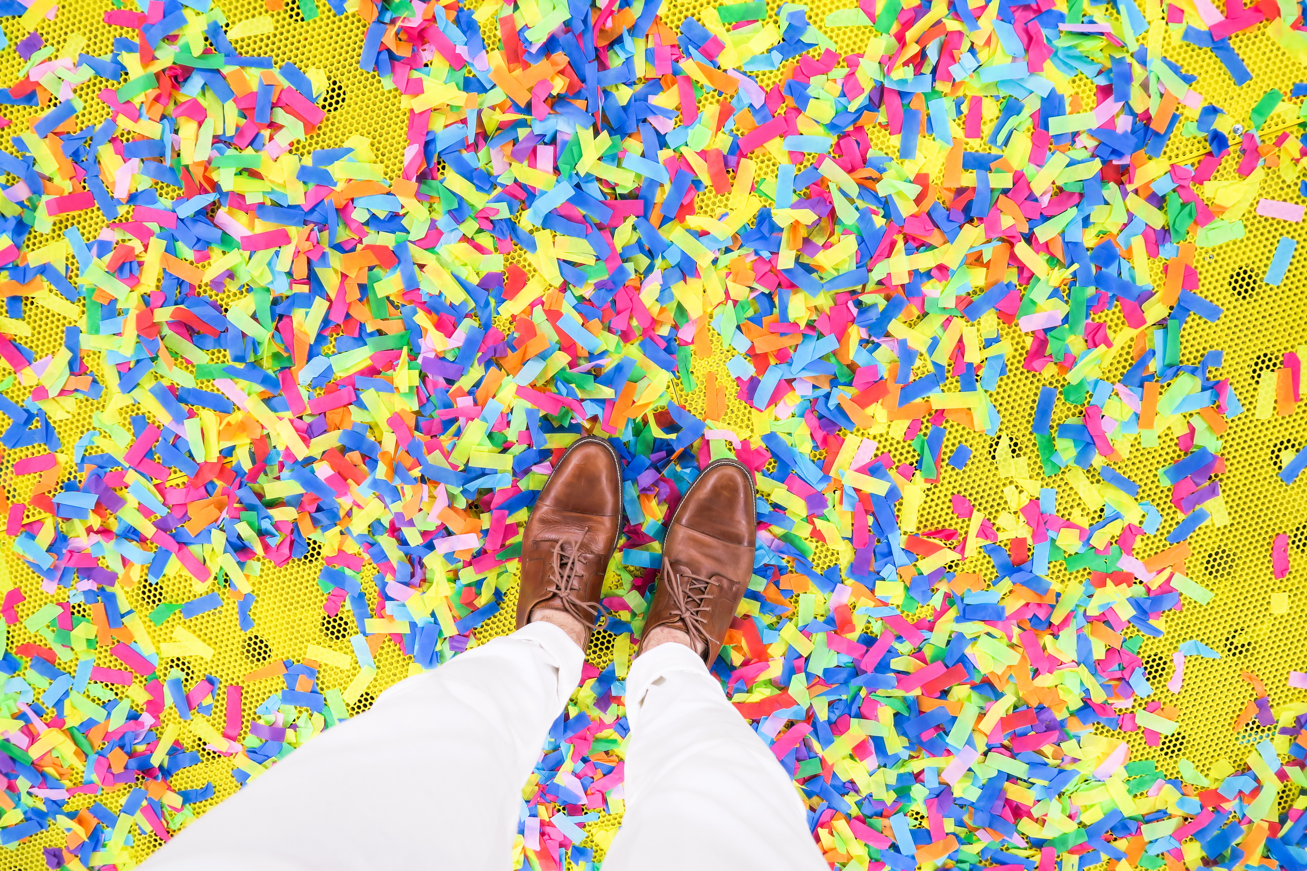Pant legs and men's dress shoes standing on colored confetti