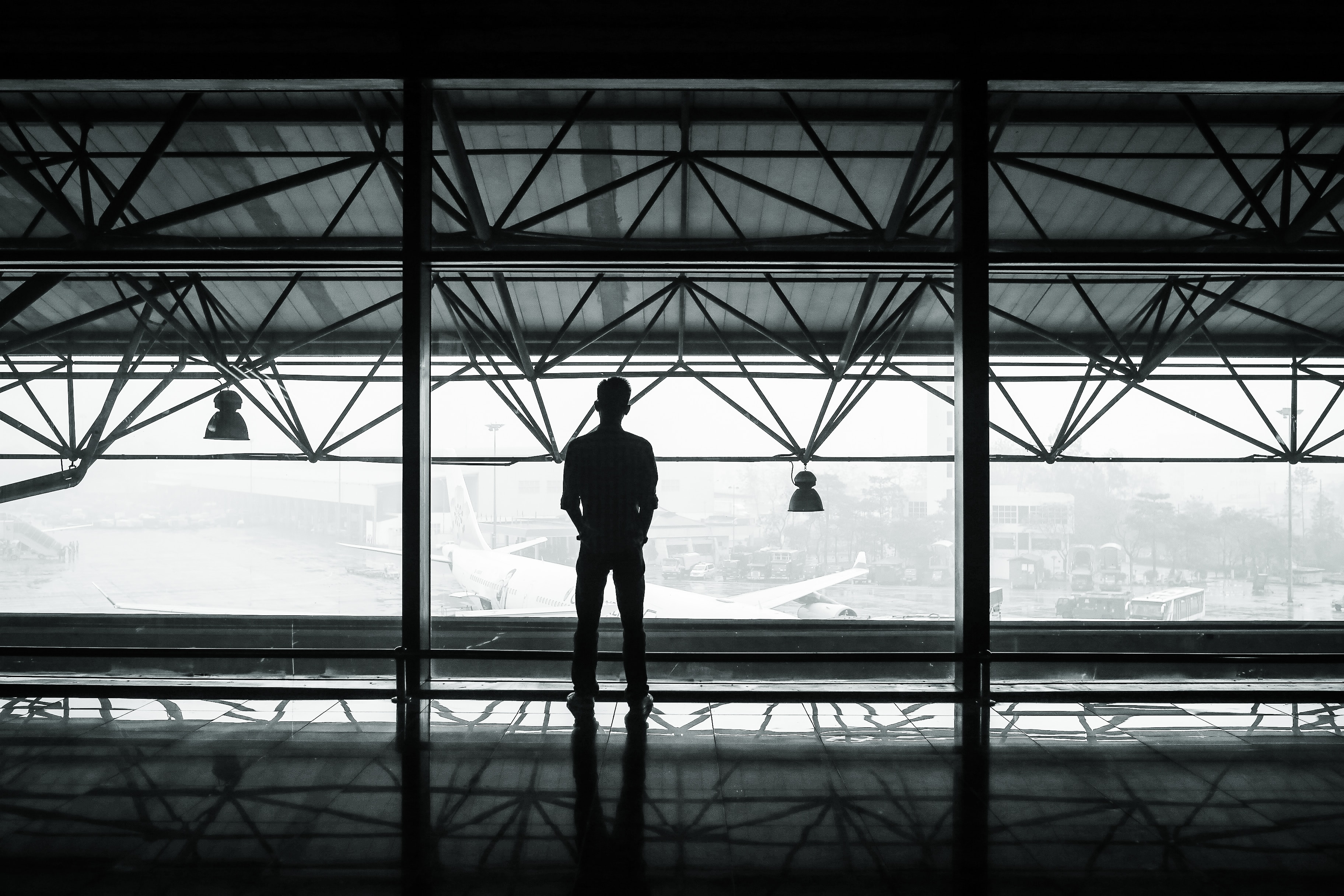 Person standing alone in black & white industrial scene.