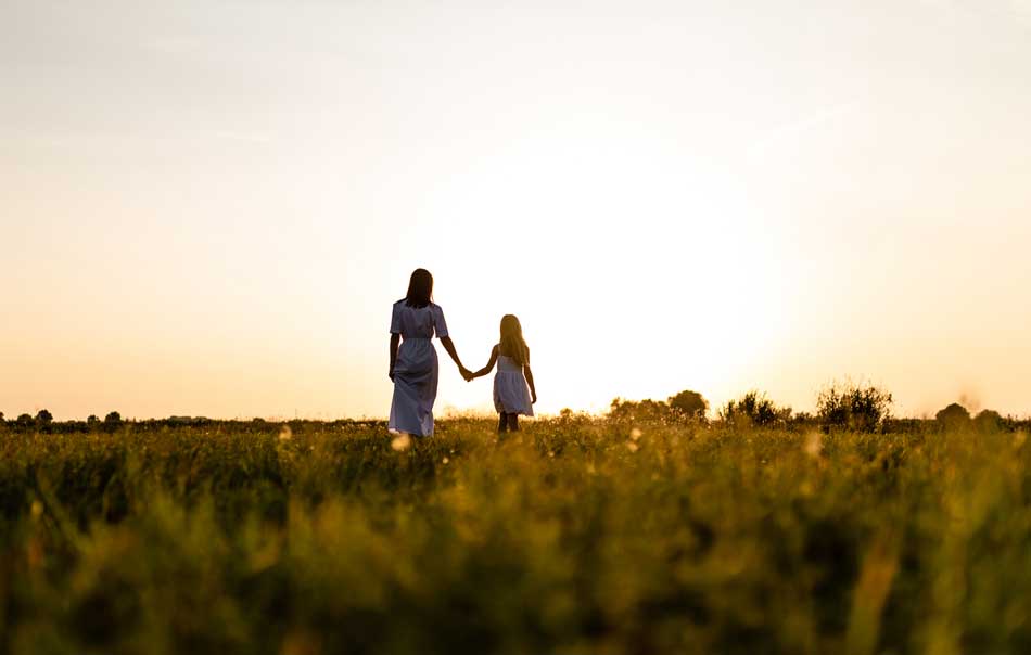 mom and daughter walking in field