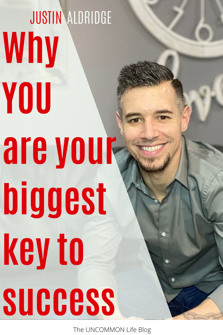 Man in grey shirt smiling with the text "Why you are your biggest key to success" in red font on the left side.
