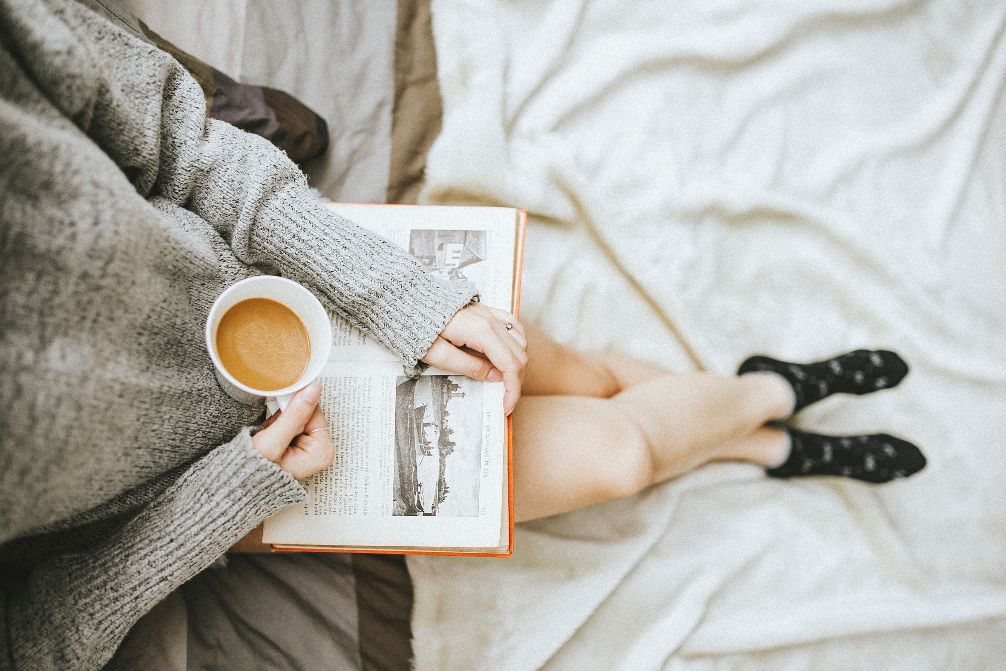 woman holding a coffee mug and reading a book