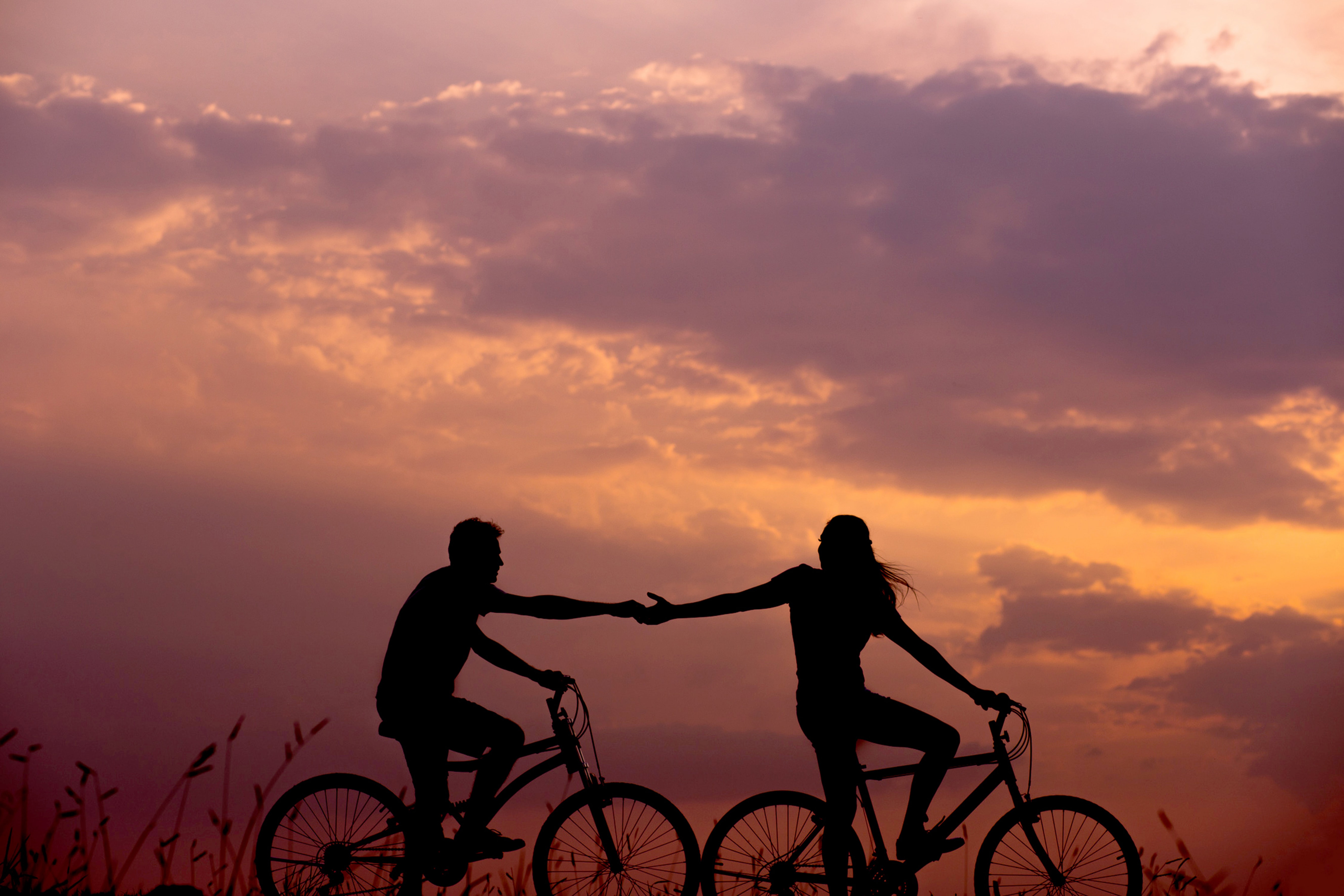 Couple riding bikes and holding hands