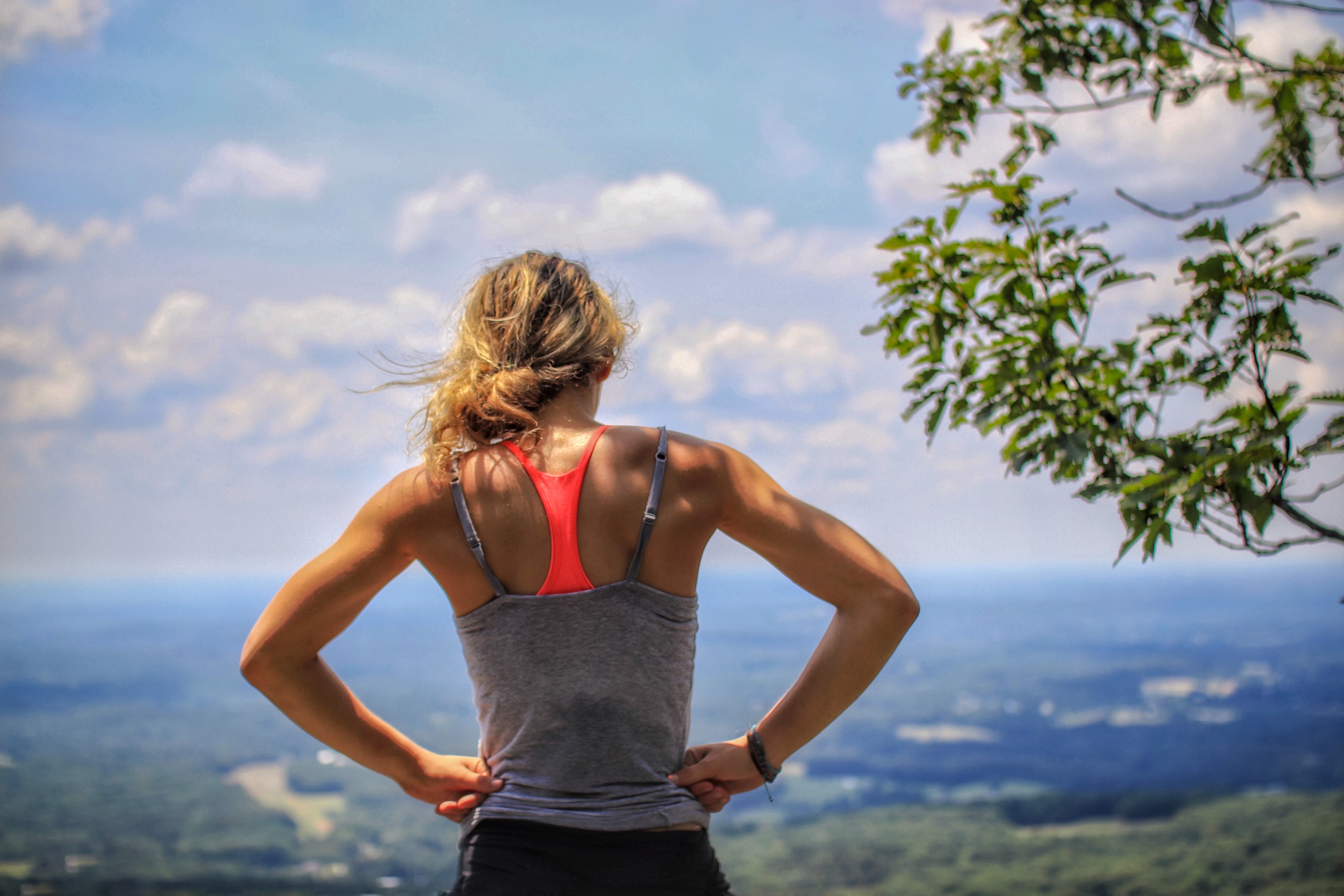 Woman standing on top of mountain looking at city below