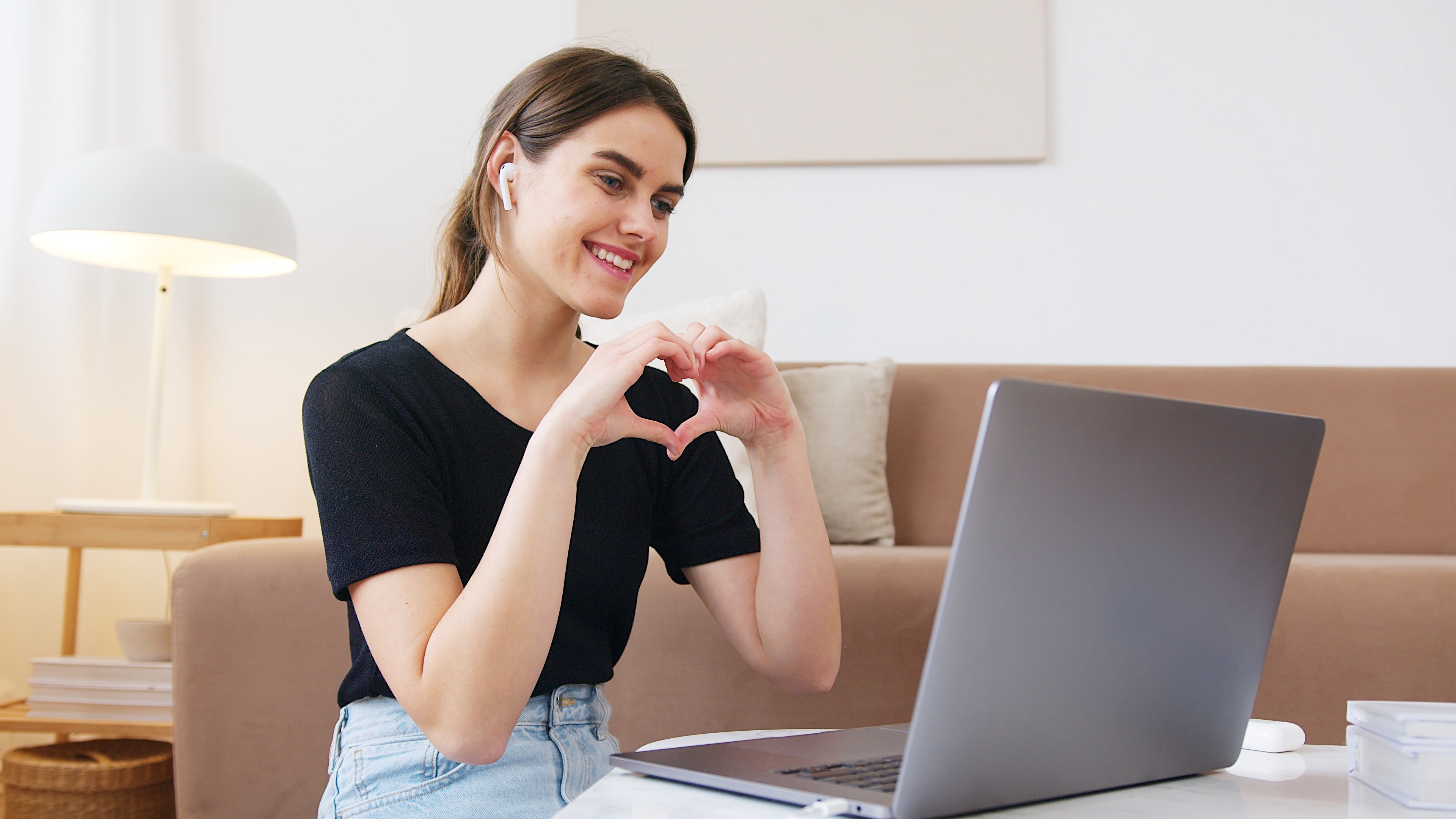 Woman makes a heart with hands while chatting online