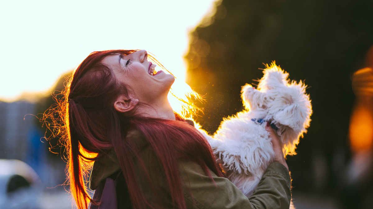 Girl laughing with fluffy white dog outdoor