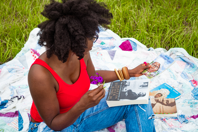 woman sitting on a blanket outdoors looking at books