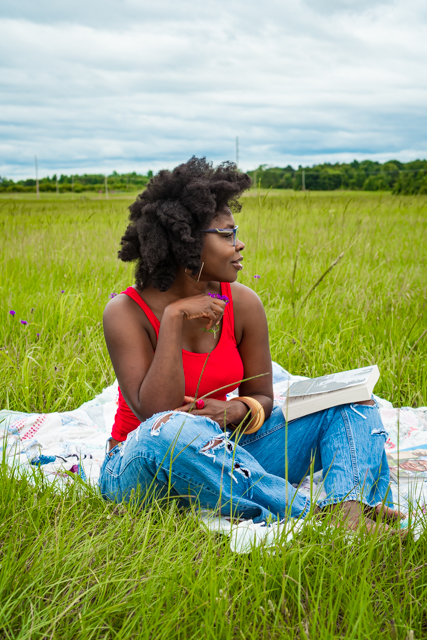 woman sitting in a gras field with books