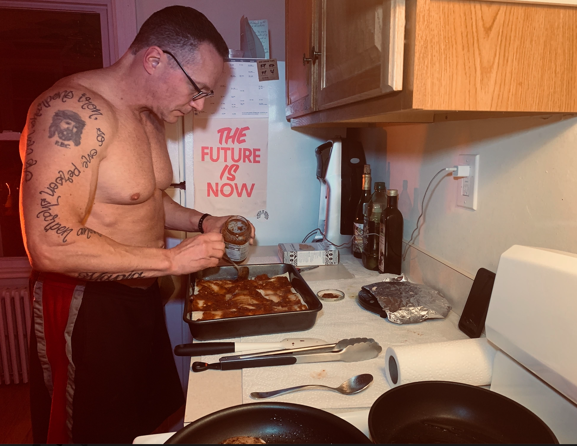 Man standing in a kitchen pouring garlic over a tray of lasagna