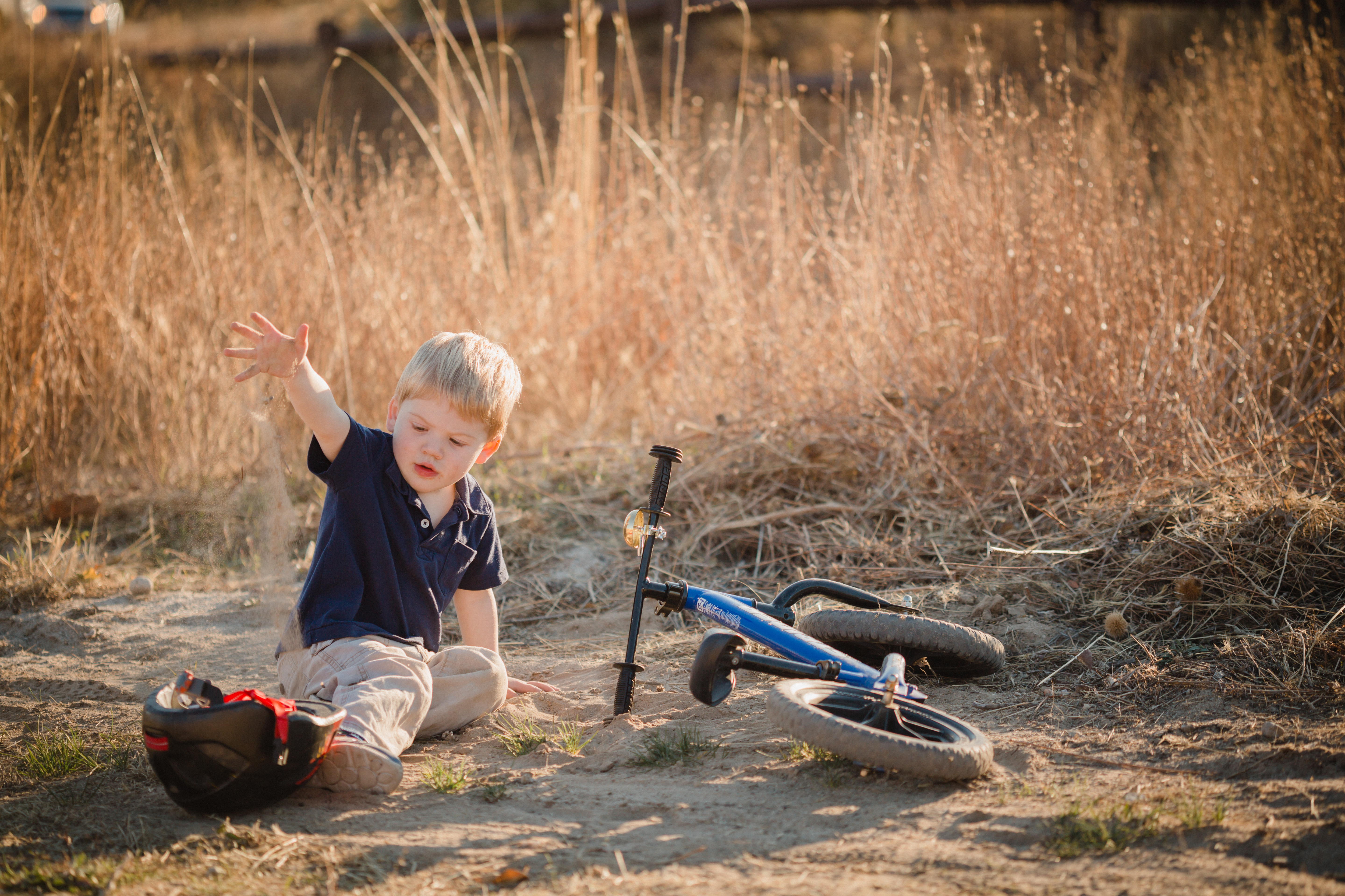 boy playing in dirt next to bike