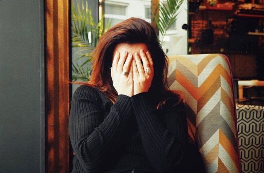 woman covering face with her hands in embarrassment