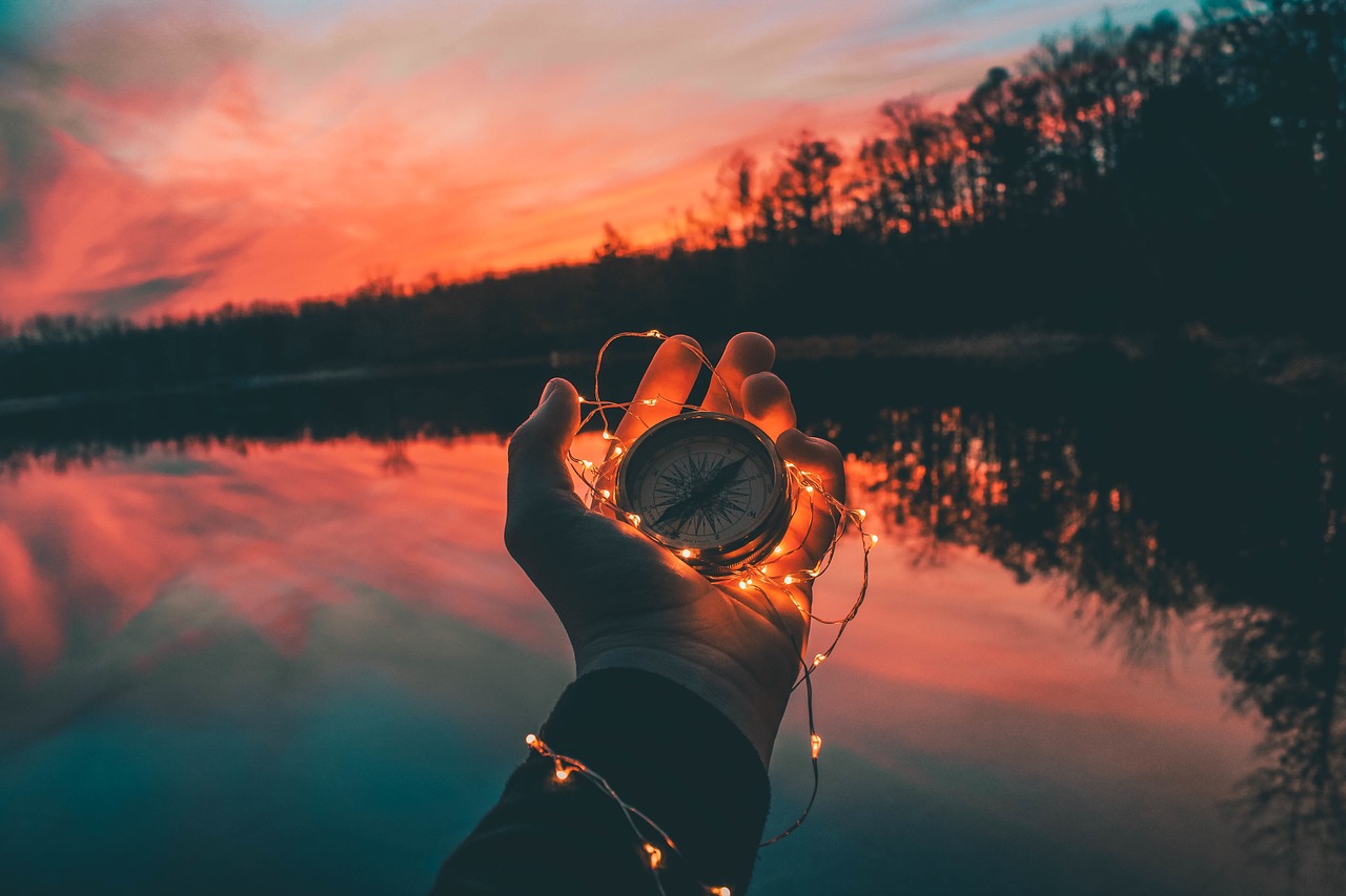 Hand holding a compass with string lights entangled