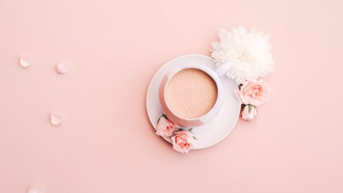 coffee, petals and small flower on pink table