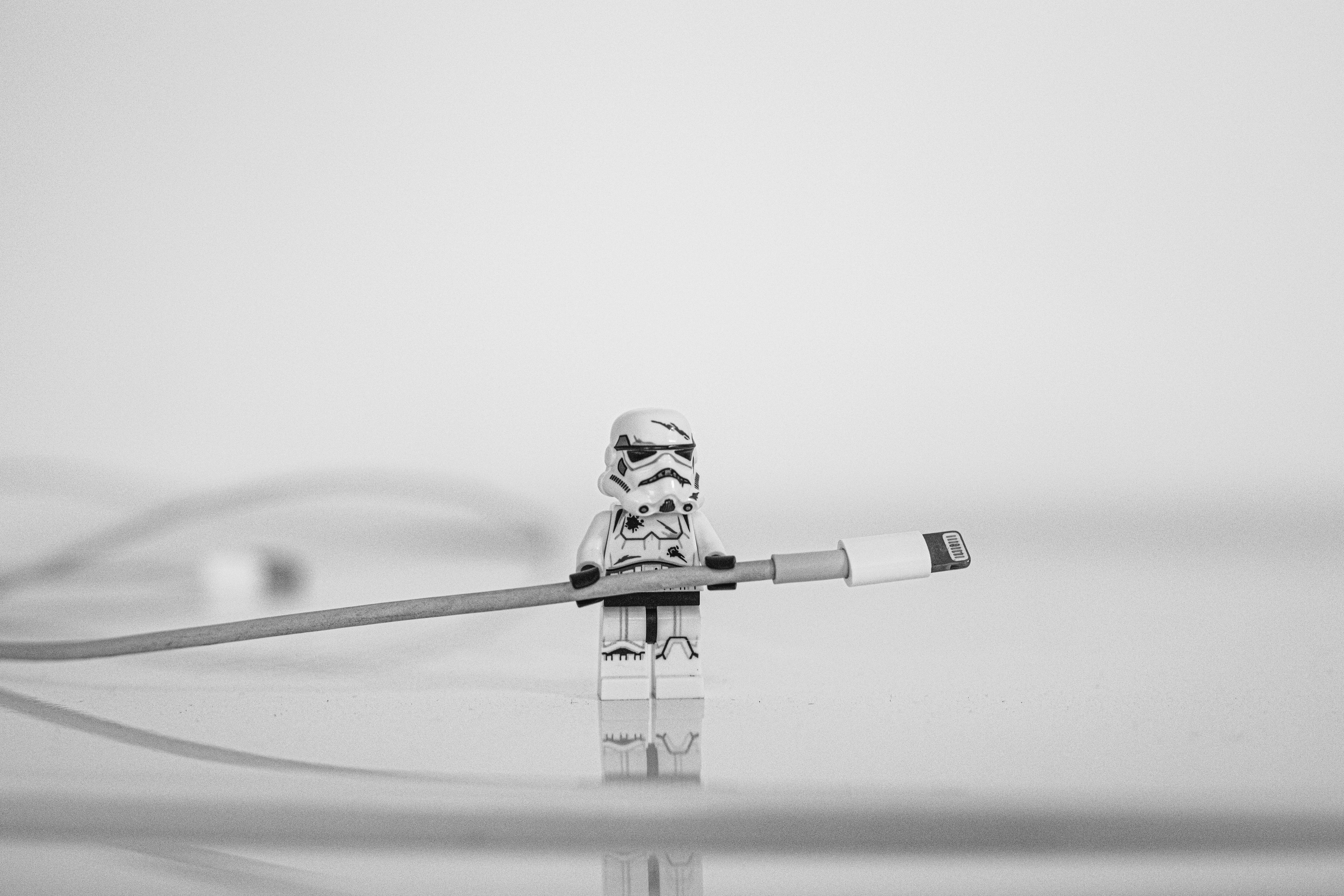 A lego storm trooper helpfully holds an iphone charger.