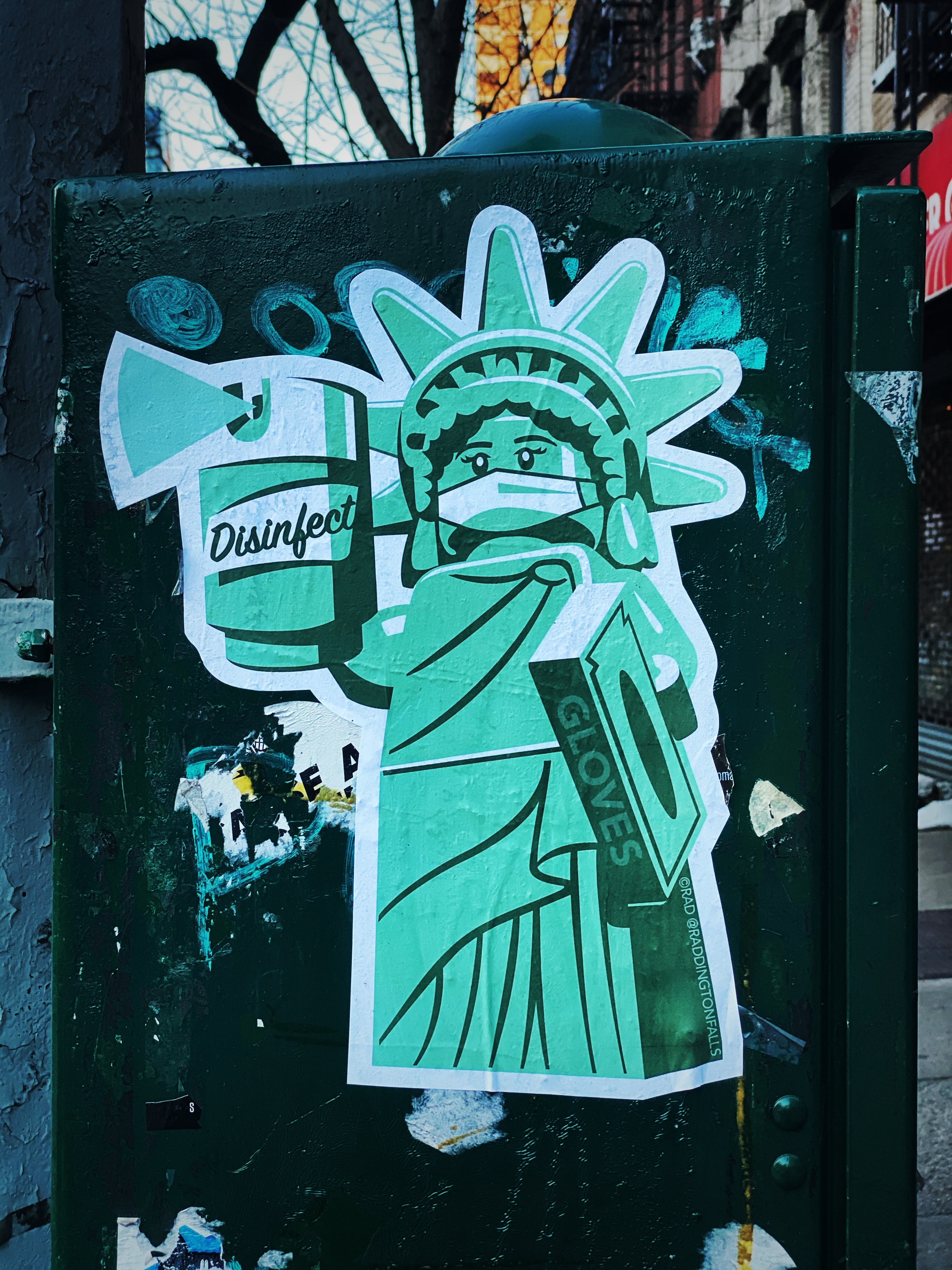 Cartoon of Statue of Liberty wearing mask and holding disinfectant spray and a box of gloves