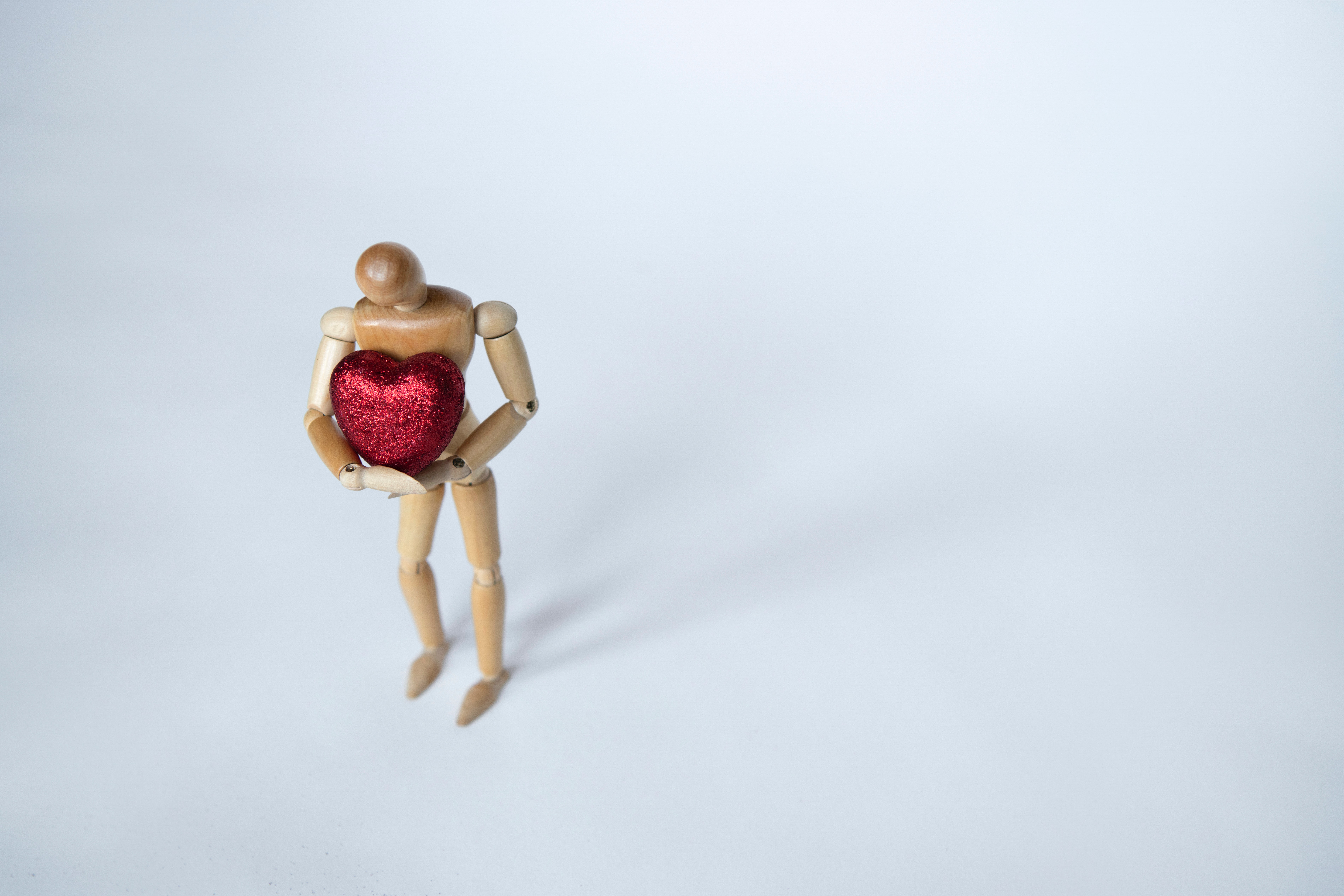 wooden figure holding a red heart