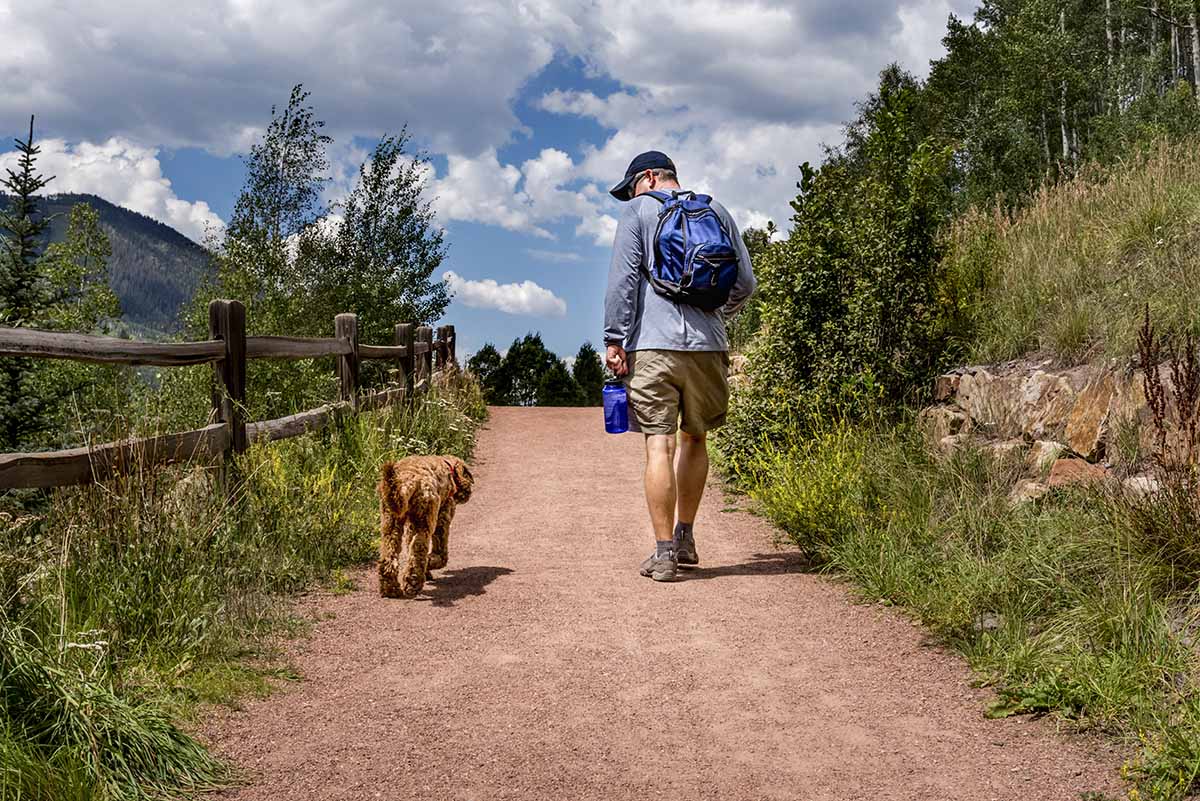 man walking dog on trail