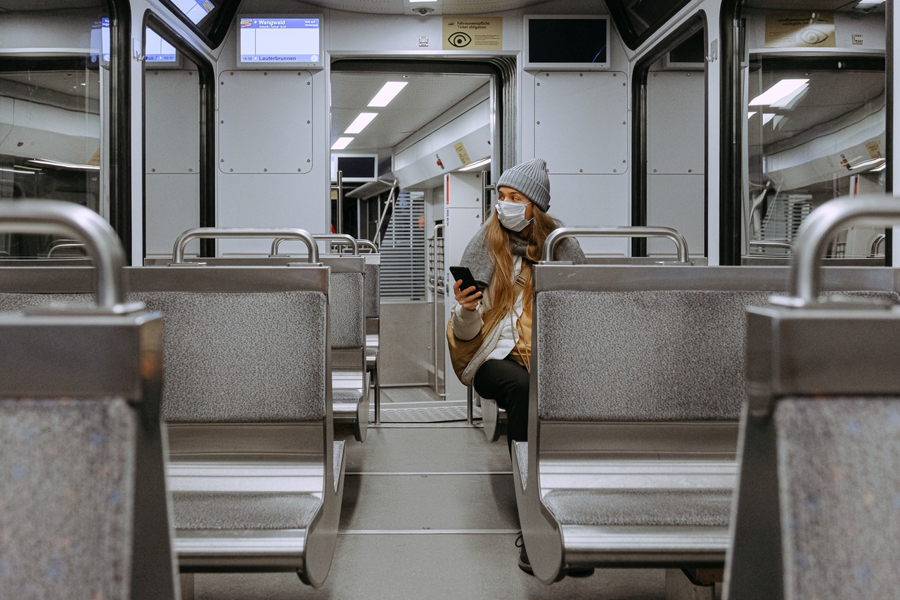 A woman with surgical mask, sitting on a metro train