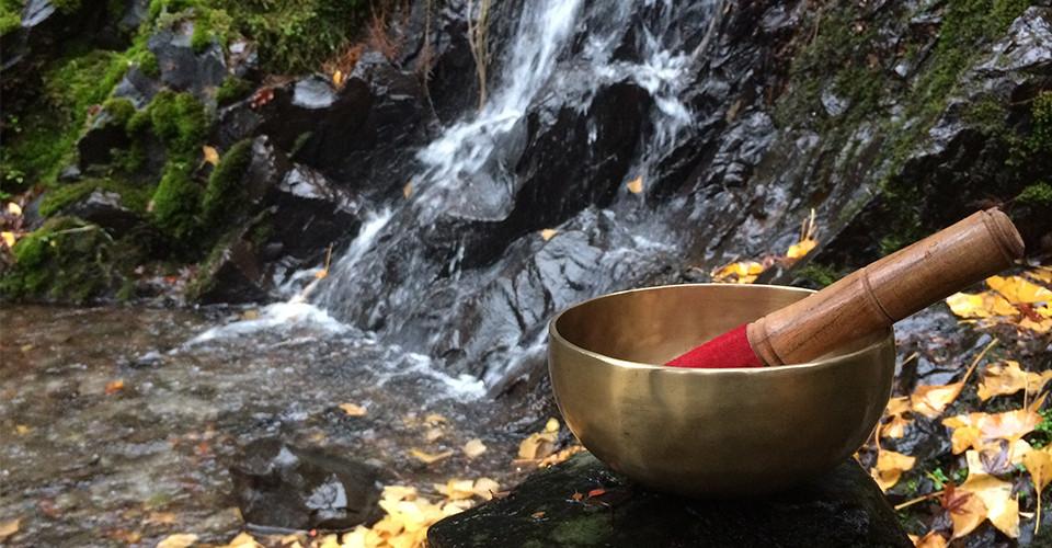 singing bowl resting on a rock by a waterfall
