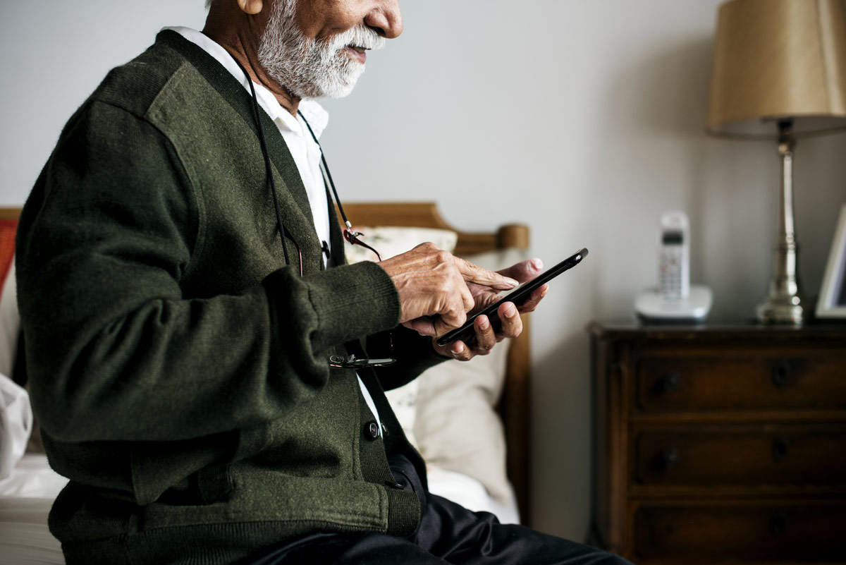 An elder man uses his cell phone to call a friend.