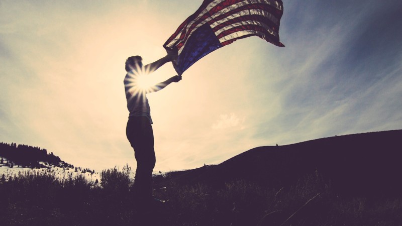 A person holding the American flag on a hill