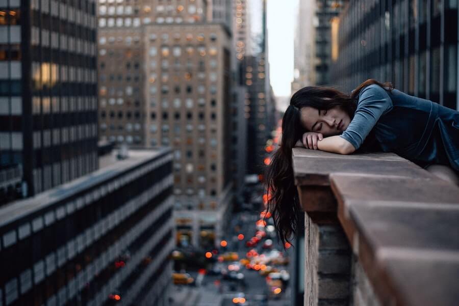 woman slumped over cityscape ledge looking depressed dealing with stress in nursing