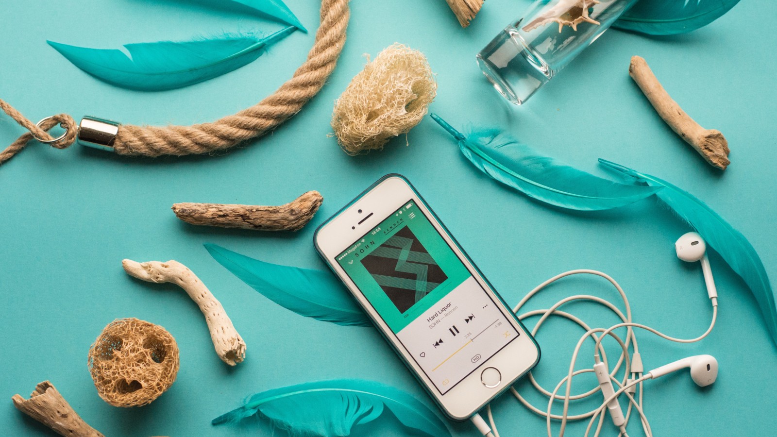 a smart phone playing a sound file with earphones attached on a background of items from the sea