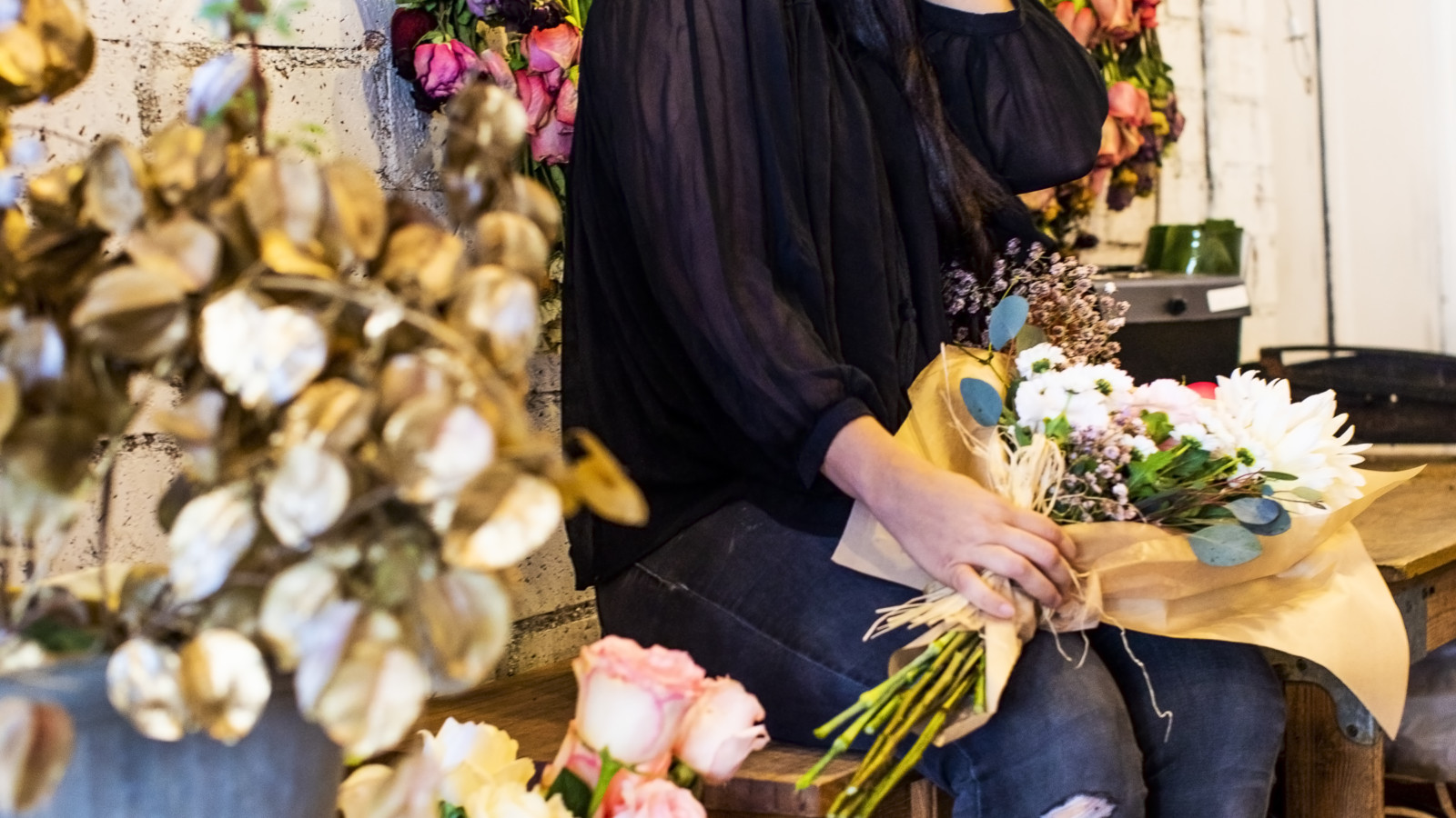 Dr. Sandra Colton-Medici sitting on bench surrounded by flowers in flower shop for Spring 2021.