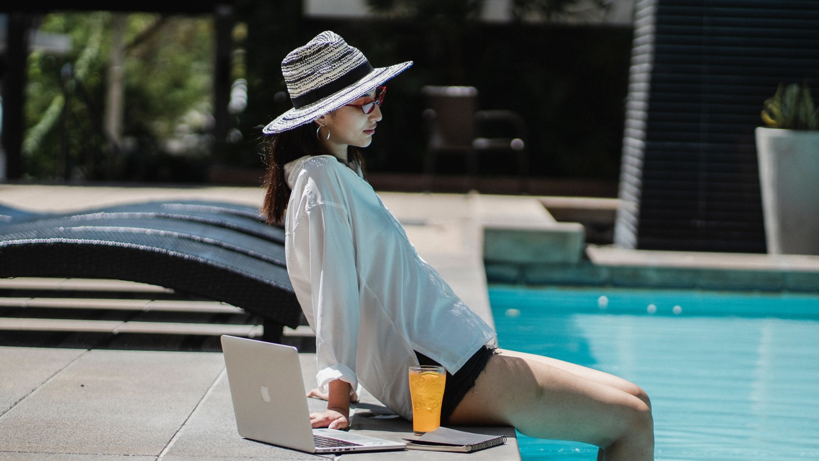 Woman relaxing by pool with laptop