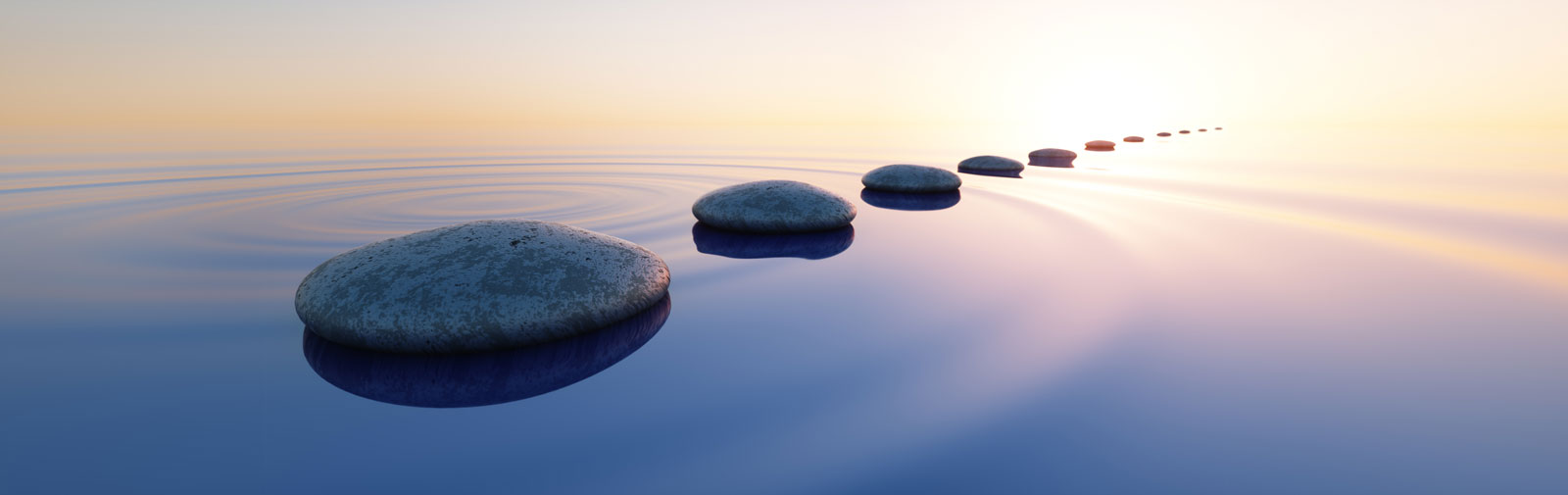 Stones set as a path through water with bright light reflecting off the water.