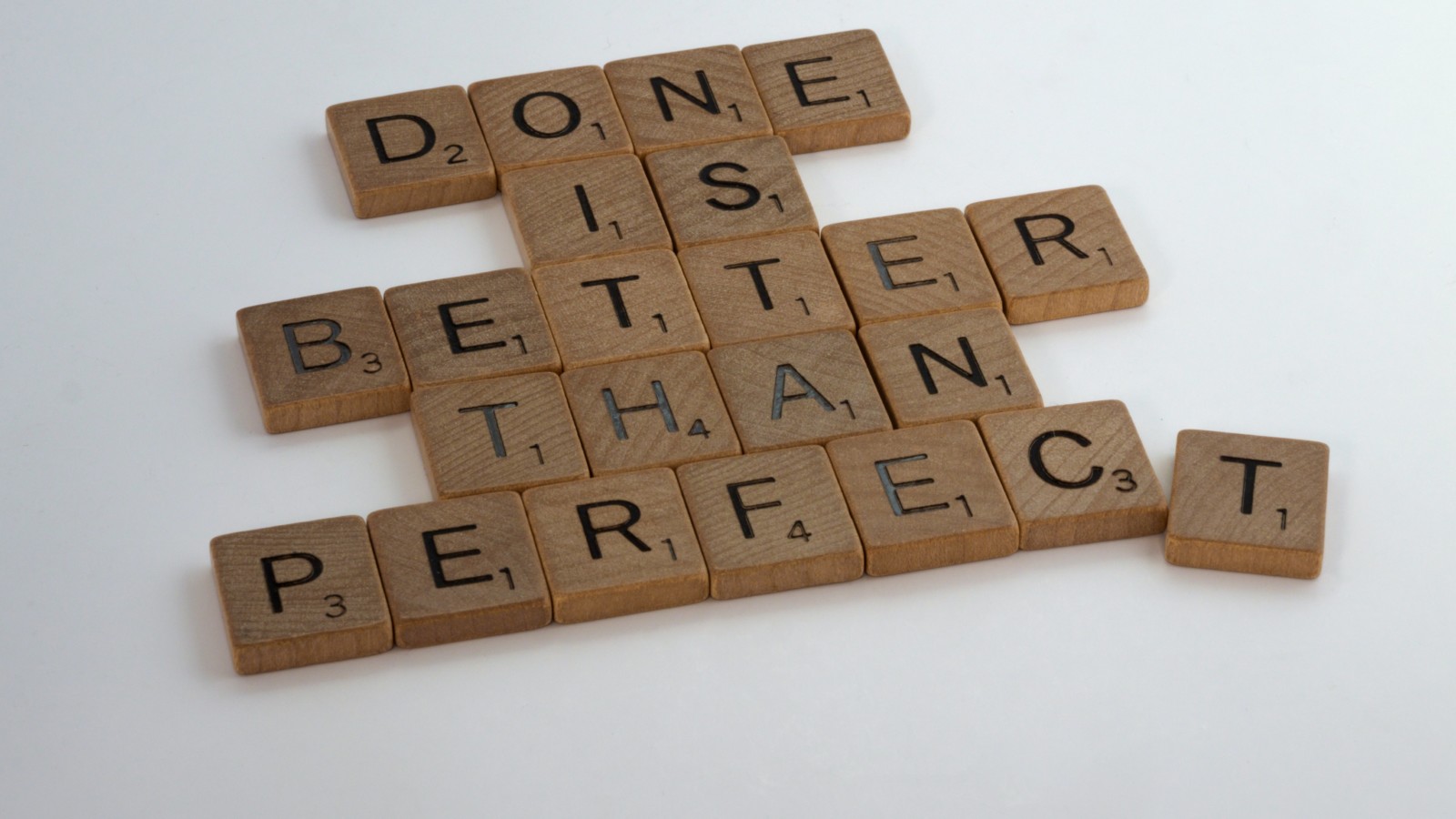 scrabble pieces spelling out "done is better than perfect"