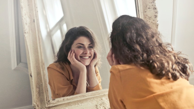 woman smiling looking into mirror