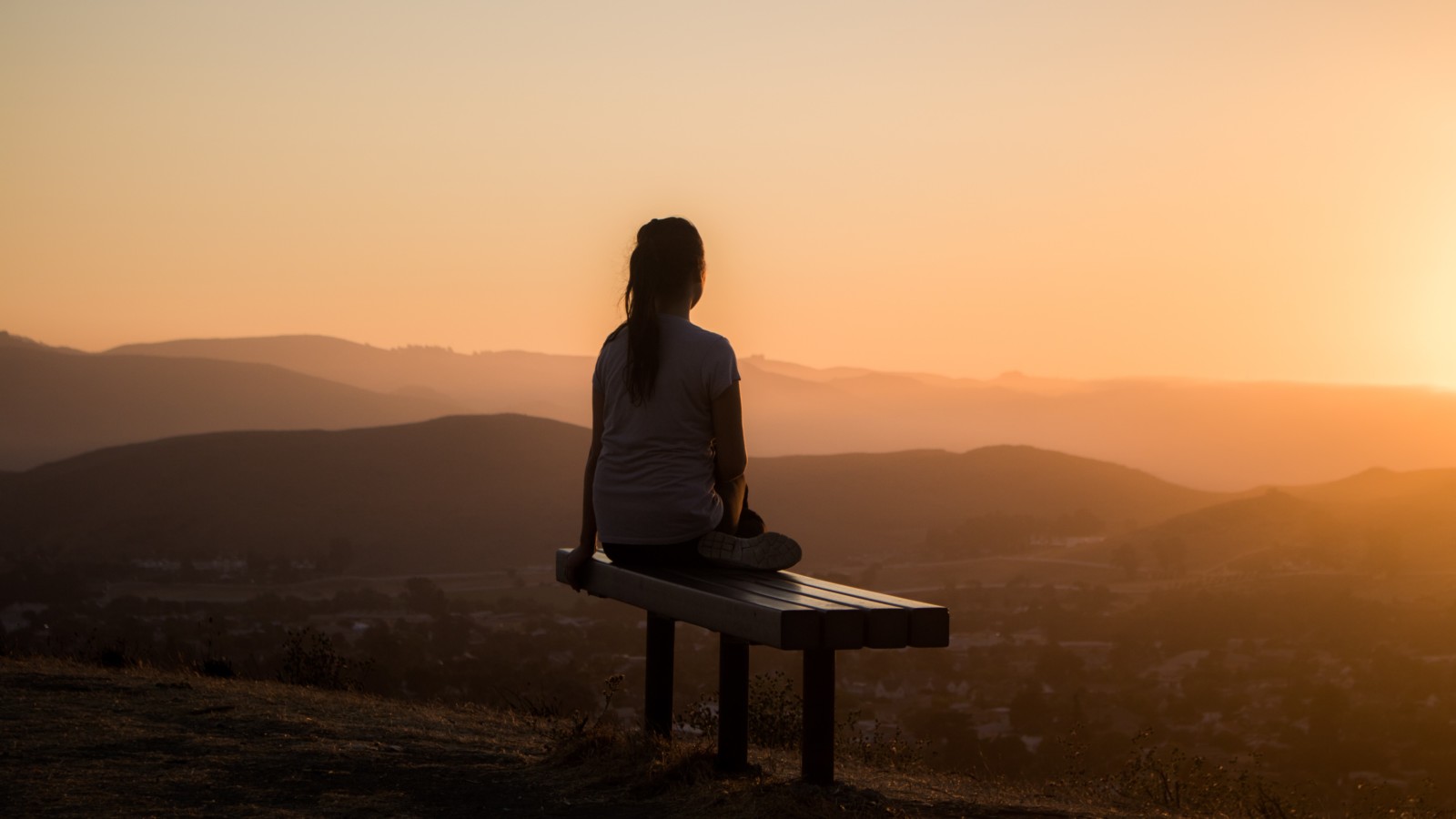 woman looking at the sunrise while meditating