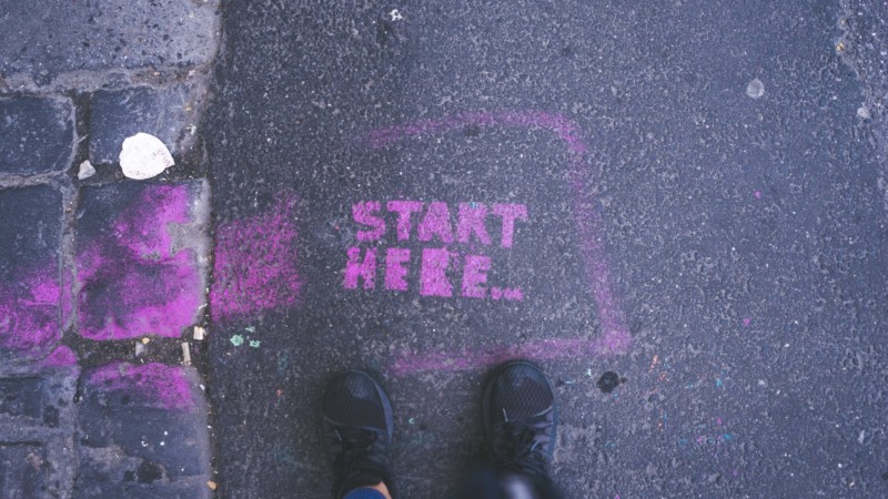 "Start Here" in purple paint on the pavement