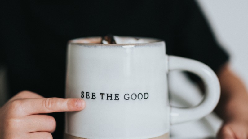 cup with be the good written on it and a faded boy in the background