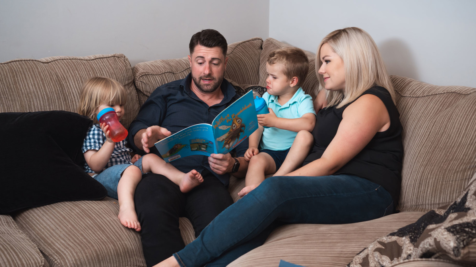Andrew Selbie and his wife reading a book to their two boys.