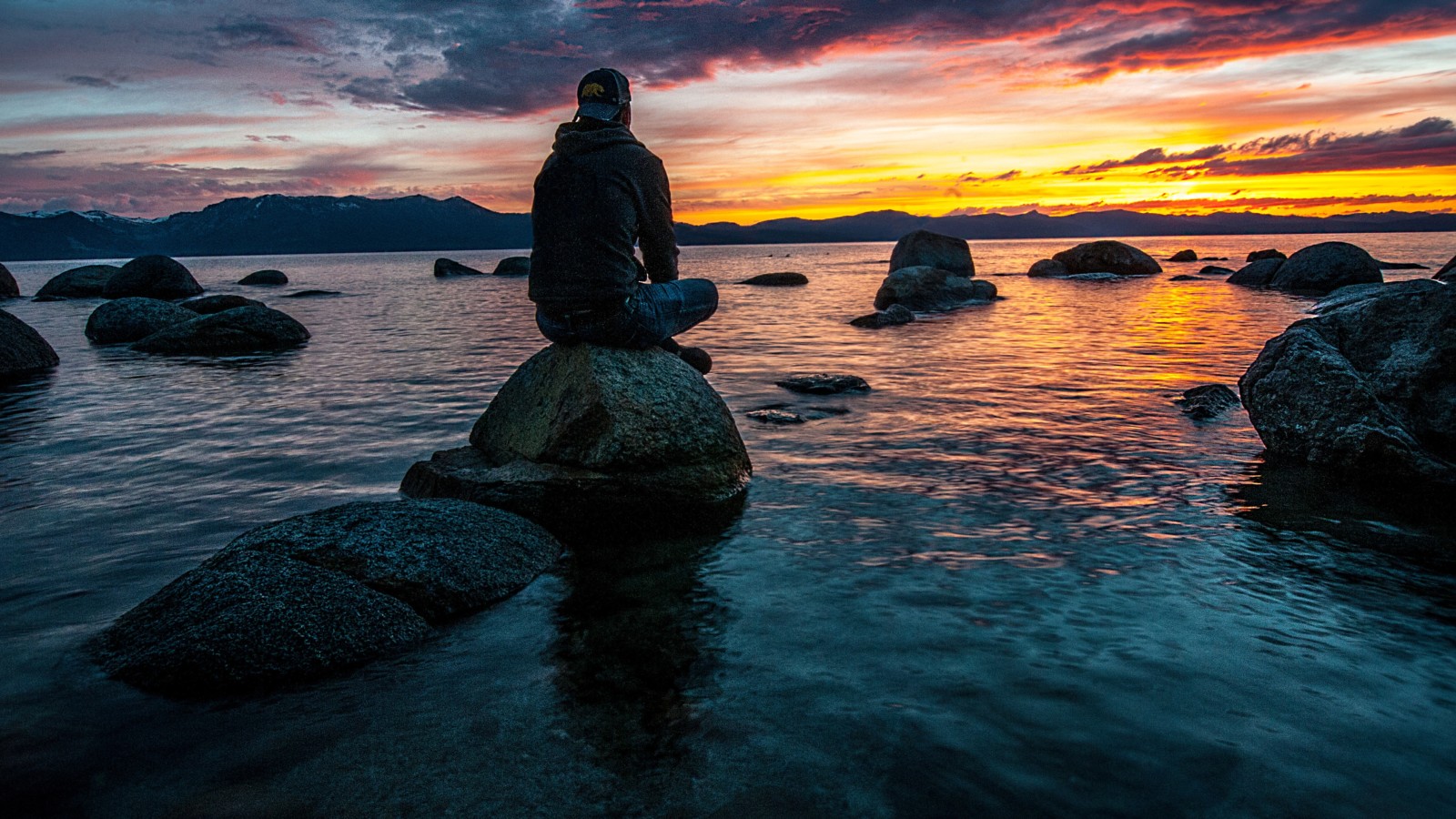 Man sitting on a rock staring at the sunset