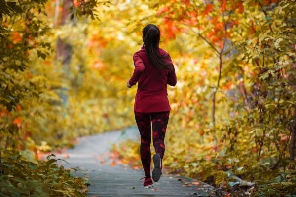 lady jogging on a trail in the fall season