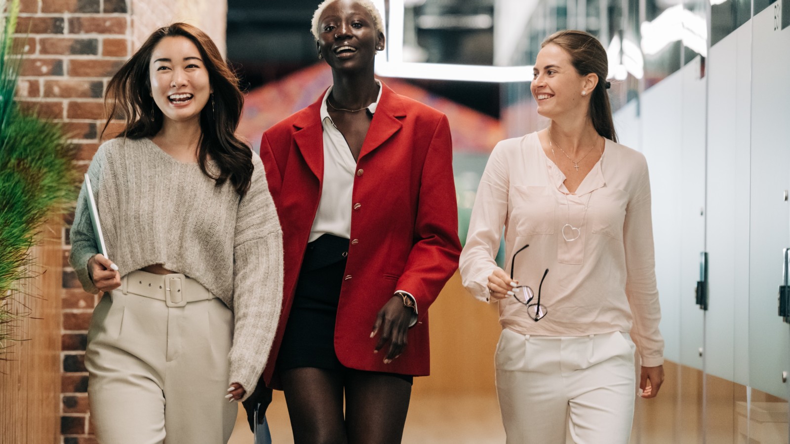 Three professional women walking side-by-side smiling
