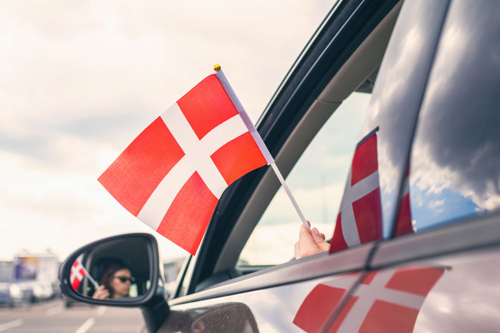 Woman waving Danish flag from her car window in Denmark. Image by © flowertiare