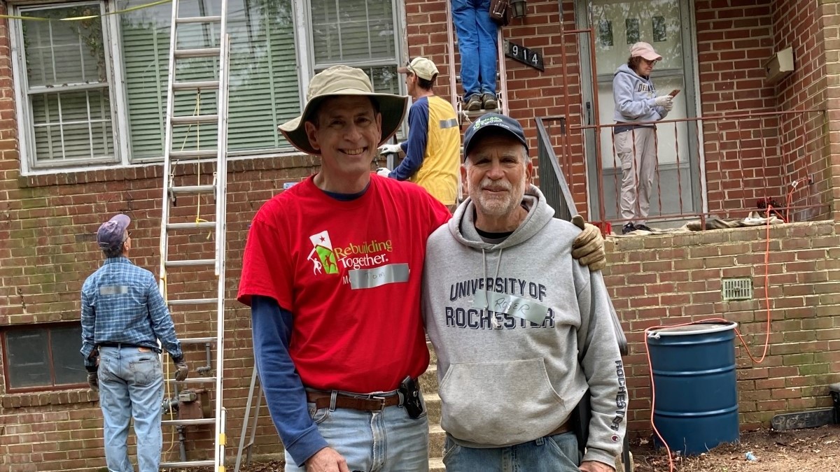 Two men standing in front of a house with construction in the background.