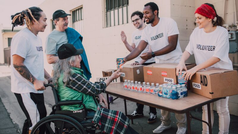 Volunteers handing out items to aid people, including a person who is in a wheelchair.