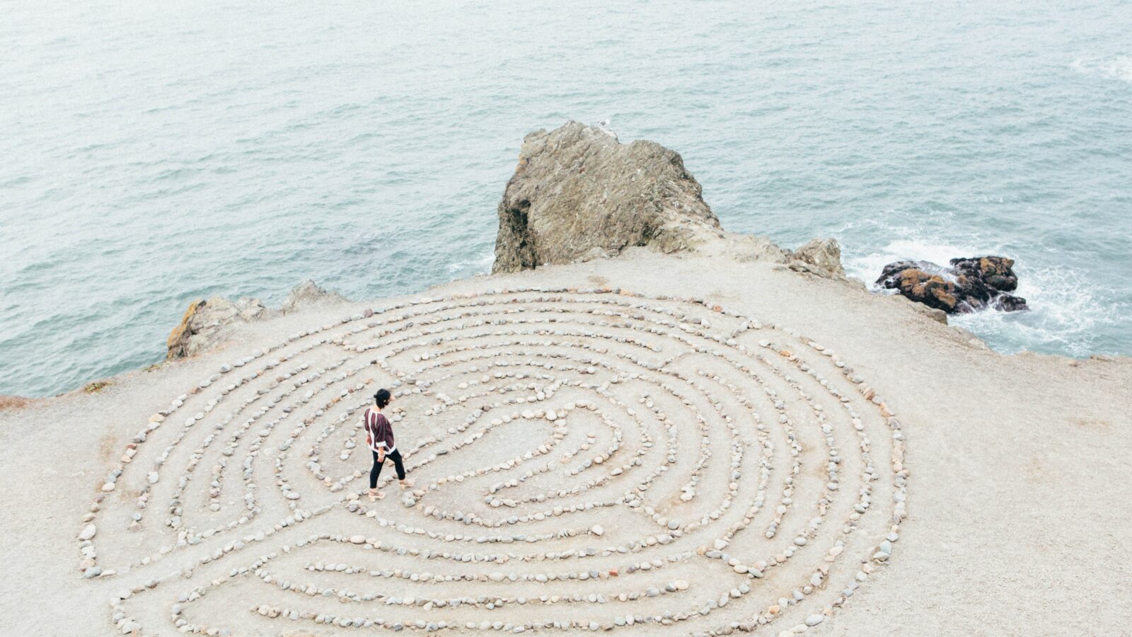 person walking in a rock maze on beach during daytime