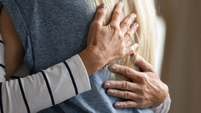 Hands on back of shirt while a person hugs another