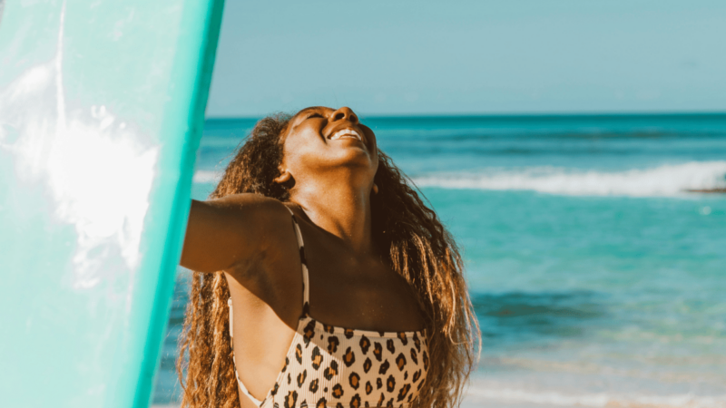 joyful-black-woman-beach-surfboard